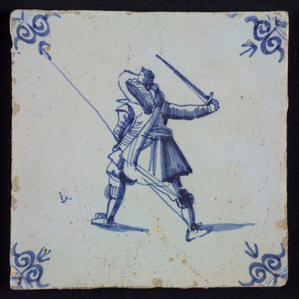 White tile with blue warrior with plume hat, spear and raised sword, seen from behind; corner pattern ox head, wall tile