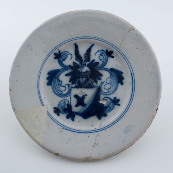 Faience plate on stand surface, decoration coat of arms with winged helmet in blue on white background, plate crockery holder