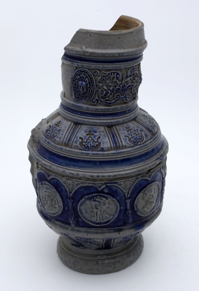 Stoneware jug with around belly arcade with portrait medallions, ear with pinched tail, cylindrical neck, jug crockery holder