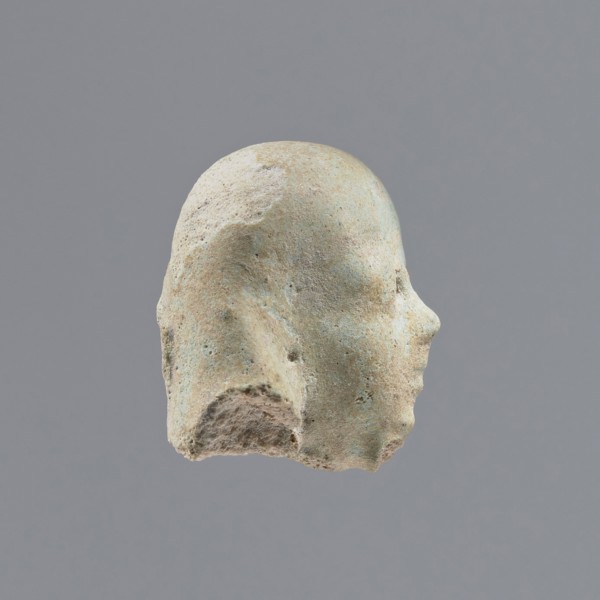 Fragment of a shabti, heads, grave goods, wigs. Head of a shabti figurine with indistinct facial