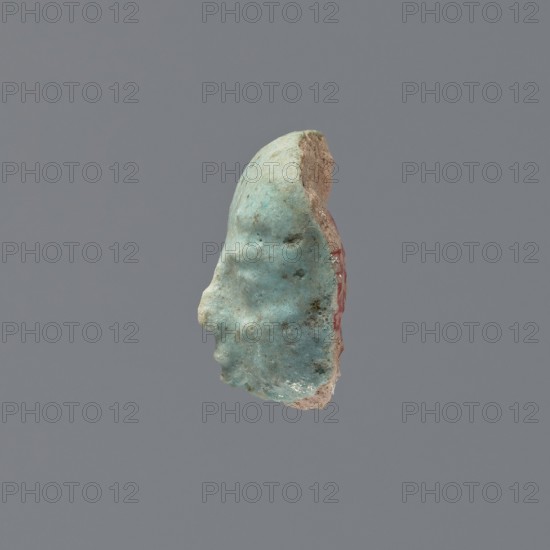 Fragment of a shabti, grave goods, wigs. Face of a shabti figurine with carefully rendered facial