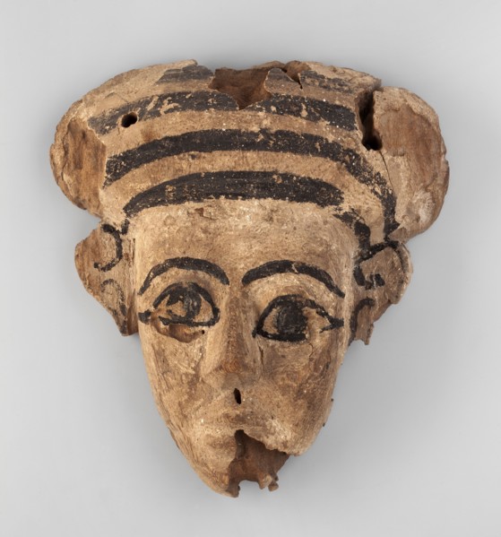 Sarcophagus mask with an elongated, triangular face. A fragment of a wig is preserved above the