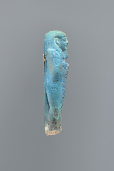 Ushabti, Mummy-shaped figurine, back supported on a flat pillar. Feet missing. Arms crossed on the