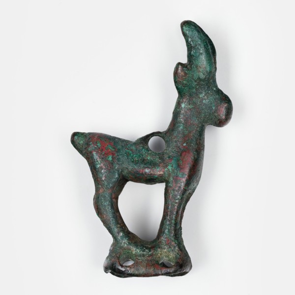 Figurine of an ibex standing on a base in the form of a hollow prism, with two pairs of holes on
