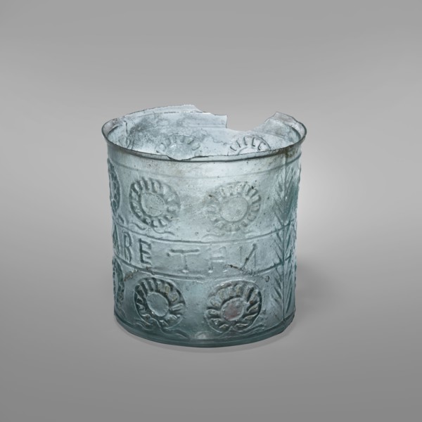 Glass with a wreath motif, Greek inscriptions. Transparent bluish-green glass decorative vessel,