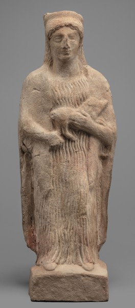 Figurine of a woman with a polos on her head, holding a piglet. Figurine of a woman standing on a