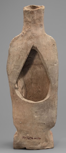 Figurine of a woman standing on a rectangular base. The woman is dressed in a finely pleated chiton