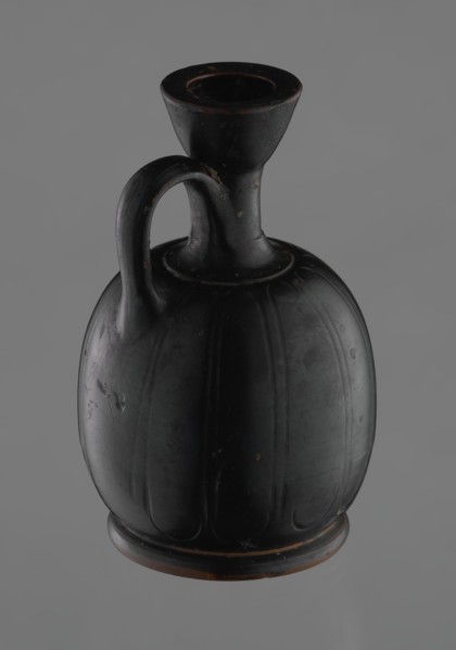 Black-finished aryballoid lekythos coated with black varnish. The medium, flat foot flows directly