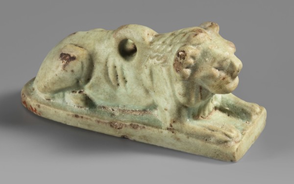 Amulet in the shape of a lion lying on a flat base, with paws stretched forward, head facing