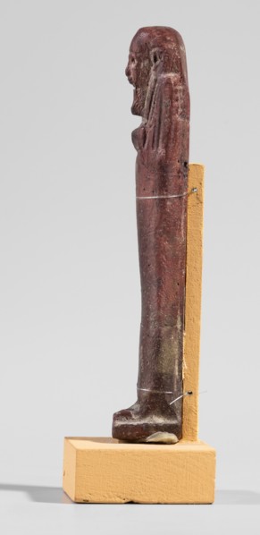 Ushabti, A shabti figurine dressed in a shroud stands on a base. On the head is a smooth wig,