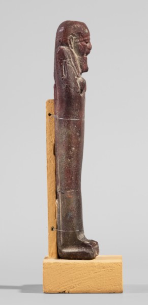 Ushabti, A shabti figurine dressed in a shroud stands on a base. On the head is a smooth wig,