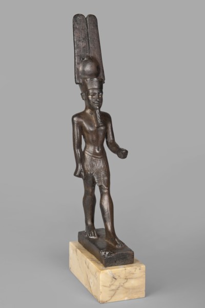 Figurine of the god Amun. Amun mythology. Figurine in a standing posture, wearing a helmet with a