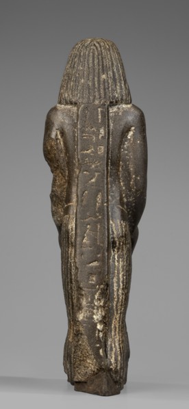 Figurine of a priest with a statuette of the god Osiris. The priest is shown standing, holding in