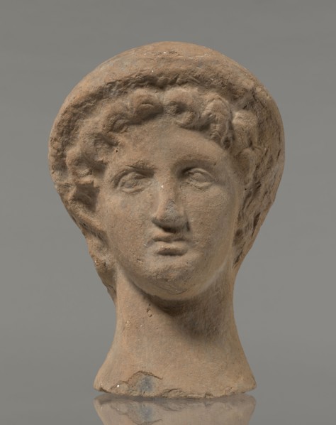 Female votive head, female head in a wreath, slightly tilted to the right shoulder. Under the