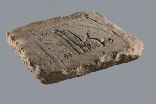 Rectangular tombstone depicting a young man in a long robe in a semi-reclining position on a bed