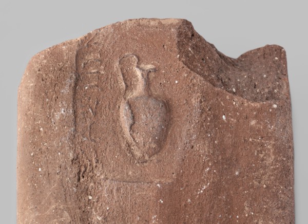 Fragment of a transport amphora vice with a stamp depicting an oinochoe and an incomplete Greek