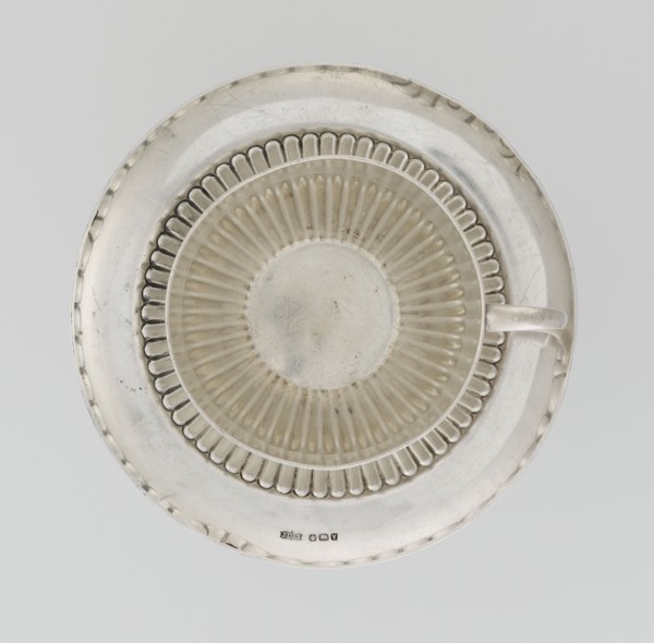 Hemispherical cup and saucer decorated with radiating curls to half its height; C-shaped side