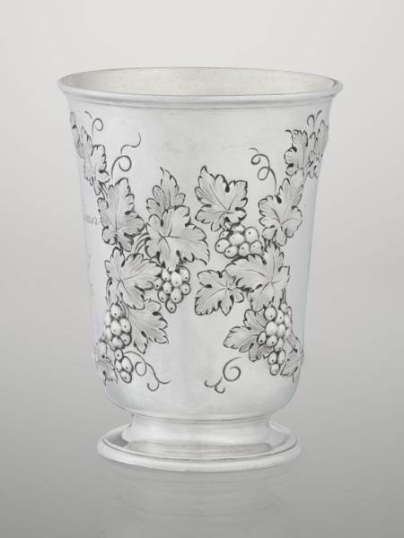 Conical mug, silver on circular foot; belly decorated with relief vine wreaths, one with an English