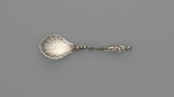 Decorative silver spoon with a shell-shaped scoop and handle formed by a solid dolphin supporting a