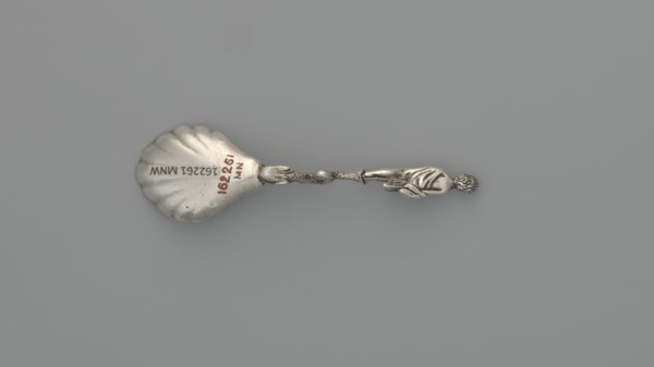 Decorative silver spoon, shell-shaped scoop, handle formed by a solid dolphin supporting a naked