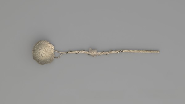 Decorative spoon with a flat round scoop with irregular edges decorated on both sides with engraved
