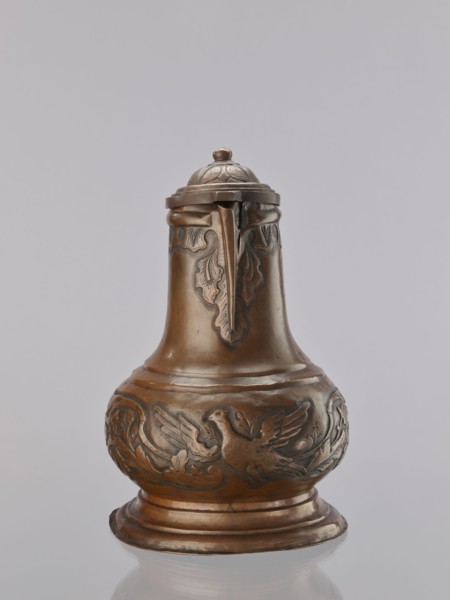 Jug. On a circular, stepped base, the body bulges in the lower part, decorated with a repoussé