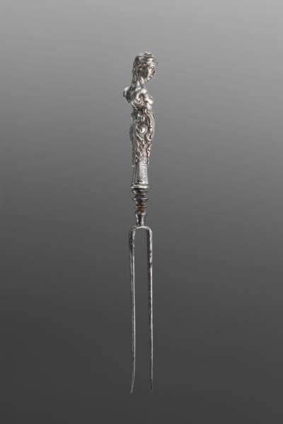 Fork. Two-pronged steel fork with a silver handle in the form of a full-plastic female herm.