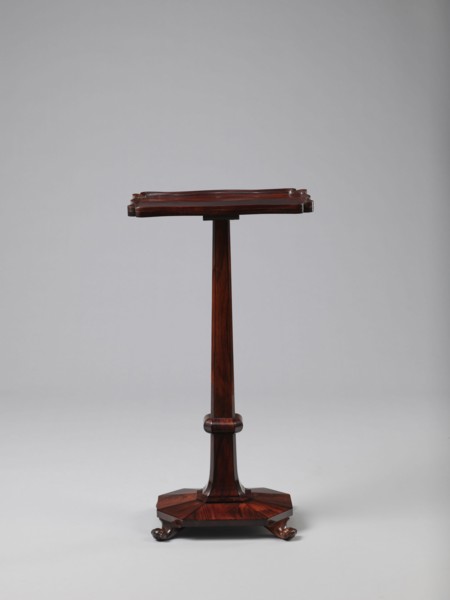 Pedestal table with a rectangular top with a wavy-cut edge and a low wooden gallery, supported by