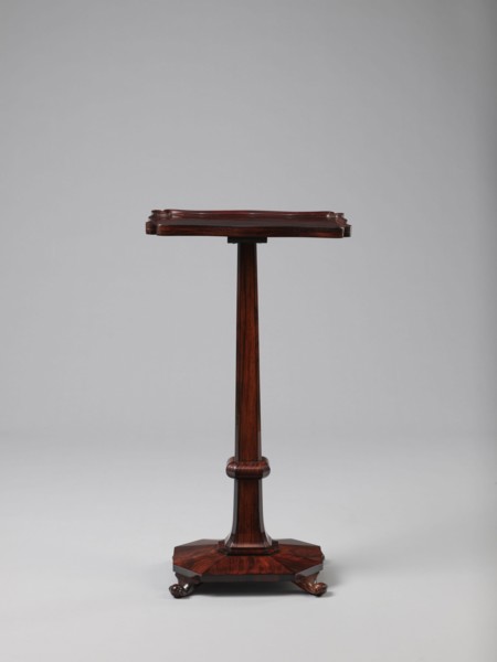 Pedestal table with a rectangular top with a wavy-cut edge and a low wooden gallery, supported by
