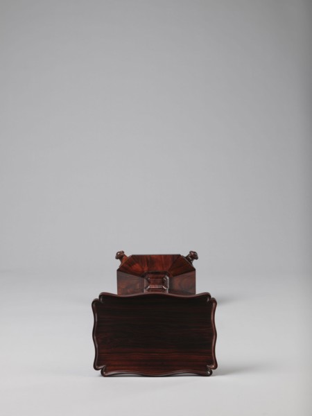 Pedestal table with a rectangular top with a wavy-cut edge and a low wooden gallery, supported by