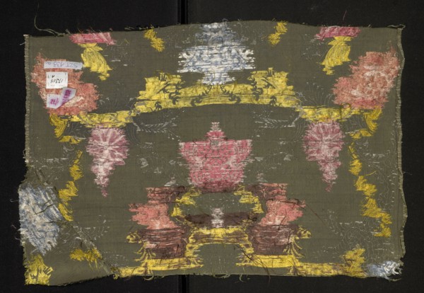Fragment of fabric, silk, patterned with floral motifs. Pattern with a symmetrical composition of
