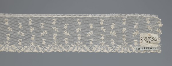 Fragment of lace, one-sided strip of edge ornament made of plant forms with a motif of a pinnately