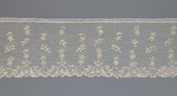 Fragment of lace, one-sided strip of edge ornament made of plant forms with a motif of a pinnately