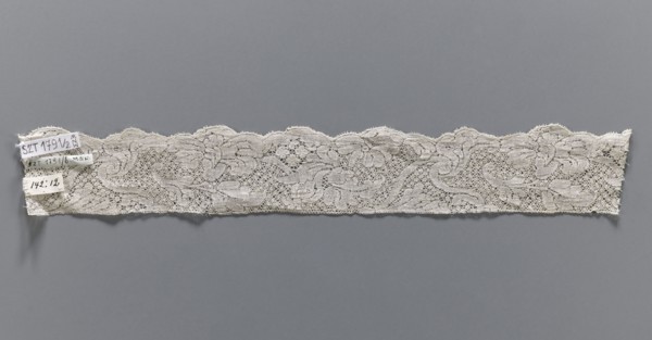 Lace fragment, bobbin lace, white, with a floral tendril ornament on a point de neige background,