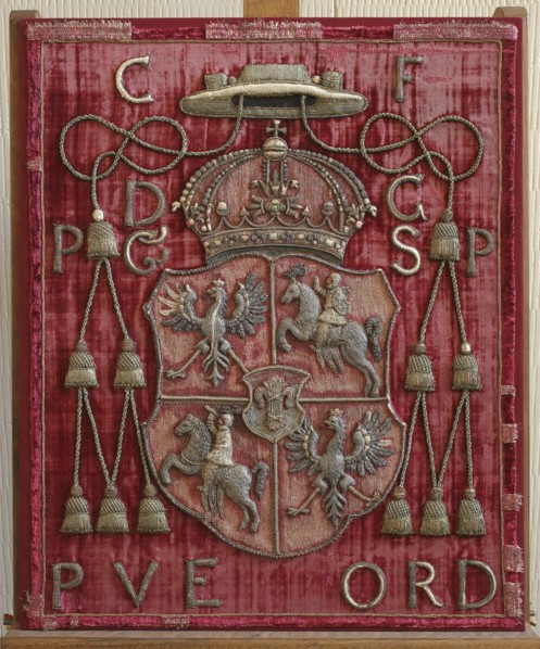 Back of a throne or bishop's chair made of red velvet with an applied coat of arms of the