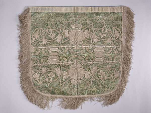 A hood from a church cope. The cope hood is made of pale green velvet. In the center, two