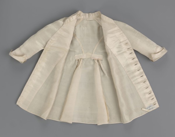 Children's dress made of cream satin. Long, fitted at the top, slightly flared at the bottom.