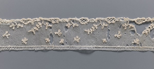 Fragment of needle lace of the point d'Alençon type. Cream needle lace with a mesh background of