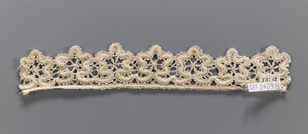 Lace fragment, needle-stitched lace, upper edge straight, lower edge serrated to match the motifs.