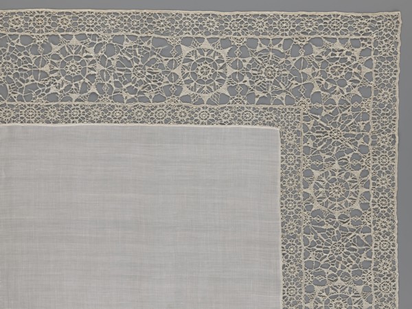Doily, smooth center. Edge made of white linen lace with rosette motifs: large rosettes in the