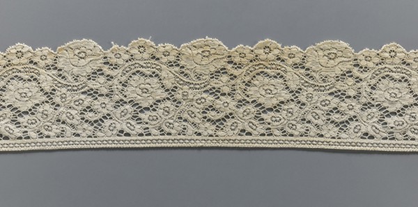 Lace fragment, machine-made lace; strip serrated on one side following the forms of rosettes and