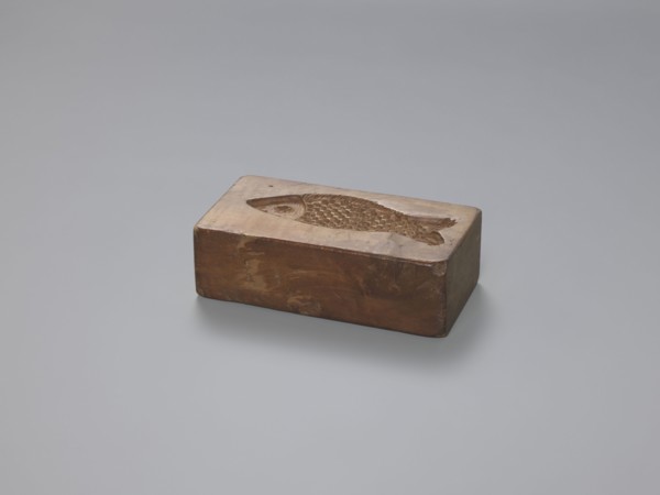 Double-sided gingerbread mould; obverse: stylised elongated fish covered with scales, shown in