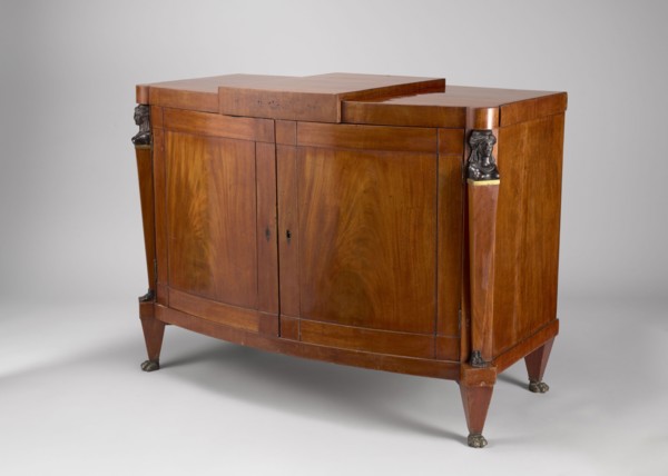 A one-piece cabinet with a slightly rounded front closed by double doors, supported by four low,