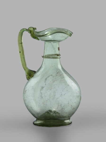 Oinochoe. Transparent, light green glass. Spherical belly on a foot with a clearance, created by