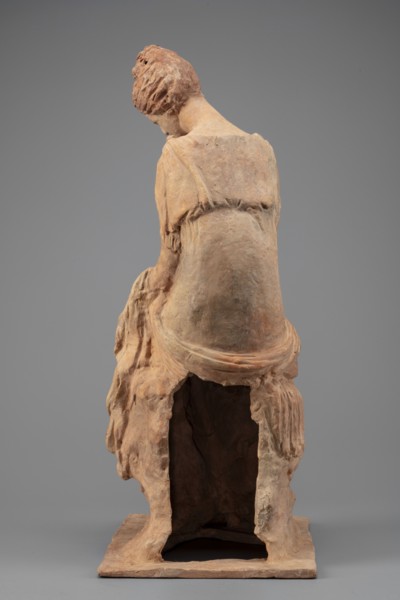 Figurine of a woman sitting on a rock with a flower in her hand. Woman sitting on a rock with a