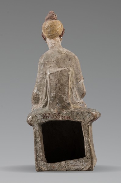 Figurine of a woman. A girl sitting in a chair is dressed in a soft white chiton over which a blue,