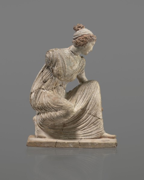 Terracotta figurine of a girl throwing dice. Figurine of a crouching girl throwing dice: weight of