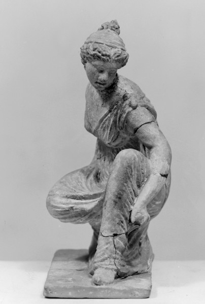 Terracotta figurine of a girl throwing dice. Figurine of a crouching girl throwing dice: the weight