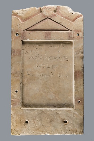 Small limestone stele with simple architectural decoration. Recessed epigraphic field surrounded by