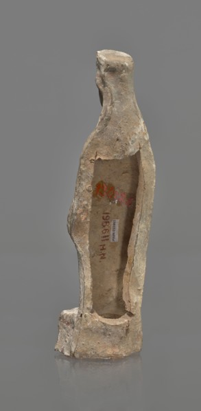 Female terracotta figurine of a standing woman, depicted frontally. Set on a small, hollow,